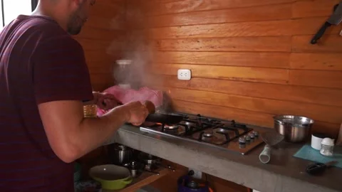 Slow motion close-up of a man sauteing a pan with oil and meats throwing a large Stock Footage 199580552