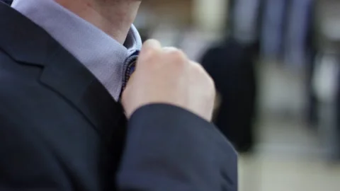 A slow motion close up of a man in a suit setting two ties to shirt's collar to 動画素材 131474864