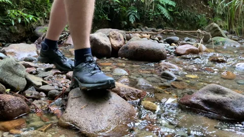 Slow motion close-up of a man's feet as he crosses a shallow stream in a forest  Stock Footage 185963359