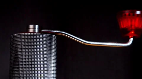 Slow motion close up of manual coffee grinder cranking on black background. Stock Footage 323571870