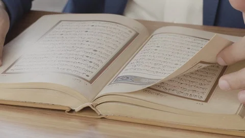Slow motion close up men's hands turning pages of holy Quran Koran Stock Footage 101388024