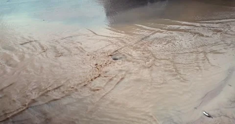 Slow-motion close-up: muddy runoff from a construction site flows rapidly. Stock Footage 336441354