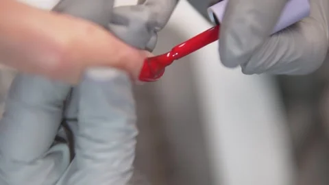 Slow motion close-up of a nail technician applying red gel polish to a clients Stock Footage 311875072