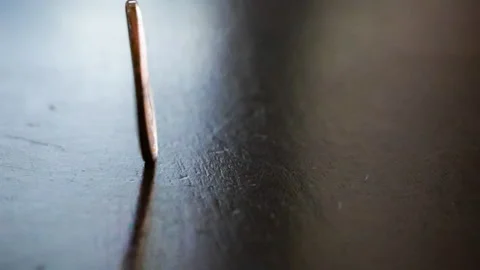 Slow Motion Close Up of a Penny Spinning on a Wood Table, Landing on Heads Видео 330811642