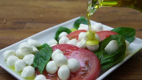 Slow motion Close up of Pouring olive oil over caprese salad 動画素材 138751786