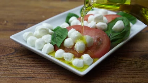 Slow motion Close up of Pouring olive oil over caprese salad 動画素材 138751832