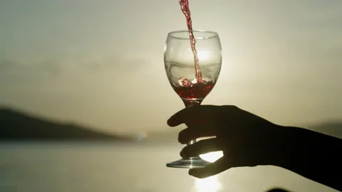 Slow motion close-up of pouring wine into a glass at sunset by the ocean. Stock Footage 201630046