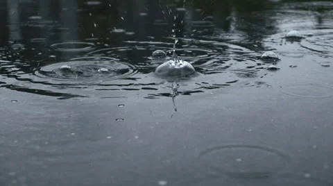 Slow motion close up, raindrops create ripples in puddle of water. Weather Rainy Stock Footage 47140149