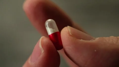 Slow Motion Close Up of Red White Antiviral Pill in Hand Stock Footage 327391997