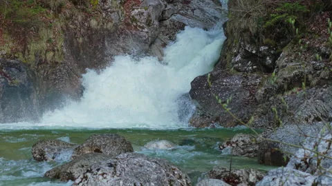 Slow motion close up of Rindbach Waterfall cascading into rocky river Ebensee Stockbeeldmateriaal 345683622