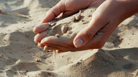 SLOW MOTION, CLOSE UP: The sand passes through the fingers of a young woman. The Stock Footage 111756177