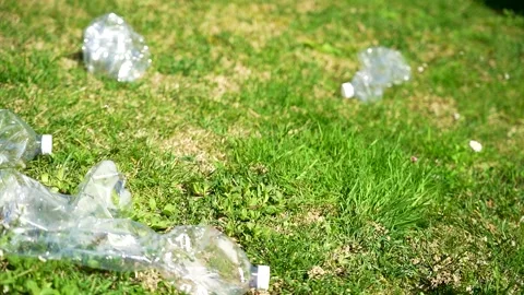 Slow motion close up of several plastic bottles falling on a green grass lawn 스톡 동영상 236879419
