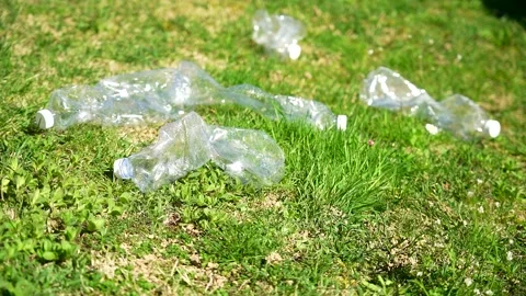 Slow motion close up of several plastic bottles falling on a green grass lawn Stock Footage 236879491