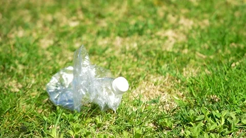 Slow motion close up of several plastic bottles falling on a green grass lawn Stock Footage 236901479