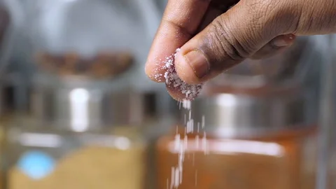 Slow motion close shot of black chef's fingers holding, sprinkling a pinch salt Stock Footage 149903533