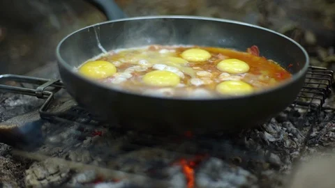 Slow-motion close-up shot frying pan stand grill campfire embers, tourists Stock Footage 110815783