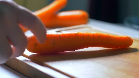 Slow motion close shot of a man’s hands peeling a raw carrot with a bladed Stock-Footage 105237850