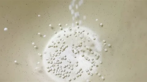 Slow motion close-up shot of pouring sago grain into a white ceramic bowl. Video stock 159442363