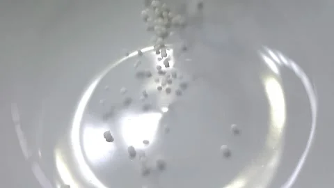 Slow motion close-up shot of pouring sago grain into a white ceramic bowl. Video stock 159442377