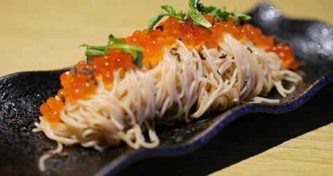 Slow motion close shot of salmon roe topping pasta on black plate Stock Footage 306129569