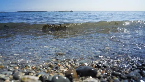 Slow motion close up shot of small waves running up on rocky beach	 Video stock 122232784