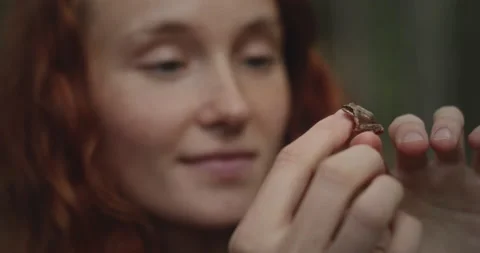 Slow motion close up shot of tiny little frog jumping from young girls hand. Stock Footage 170506484