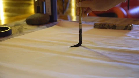 Slow motion, close-up shot of a woman's hand using a large ink brush to Video stock 110831840