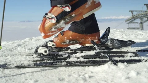 SLOW MOTION CLOSE: Skier steps in ski bindings with ski boots at resort in Alps Stock Footage 80873036