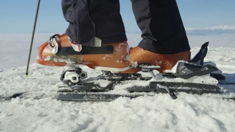 SLOW MOTION CLOSE: Skier steps into the ski bindings with ski boots on the piste Stock Footage 80873049