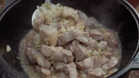 Slow motion close-up of stirring fried lamb meat with onions in cauldron du.. Stock Footage 319660667
