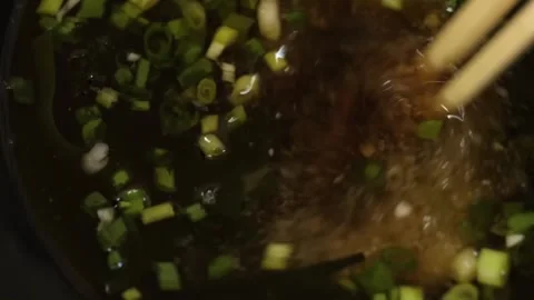Slow Motion Close-up of Stirring Vegetable Manchow Soup with Chopsticks Stock Footage 333524471