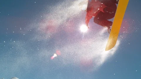 SLOW MOTION CLOSE UP: Stunning snowboarding jump over winter sun and blue sky Stock Footage