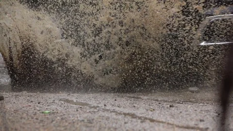 SLOW MOTION CLOSE UP: SUV car tyres driving over deep puddle and splashing water Stock Footage 80032848