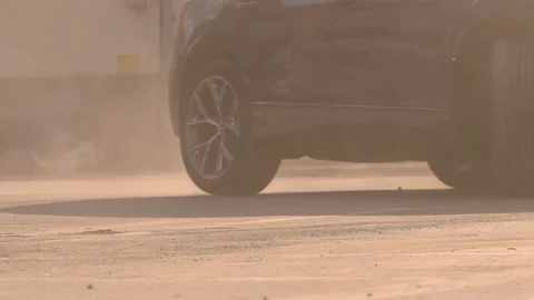 SLOW MOTION CLOSE UP: SUV car starts and quickly drives away from a dusty Stock Footage 129196043