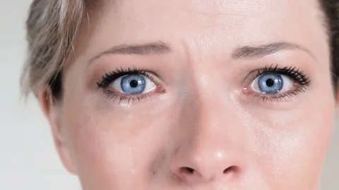 Slow motion close up: Tear comes out of an eye and streaks down the cheek Stock Footage 74553961