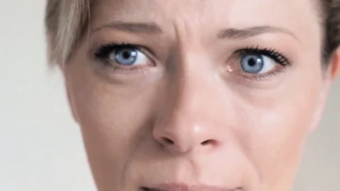 Slow motion close up: Tear comes out of an eye and streaks down the cheek Stock Footage 74554865