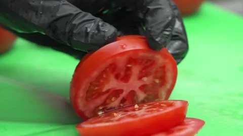 Slow-motion close-up of a tomato being expertly sliced with a sharp blade Stock Footage 331633564