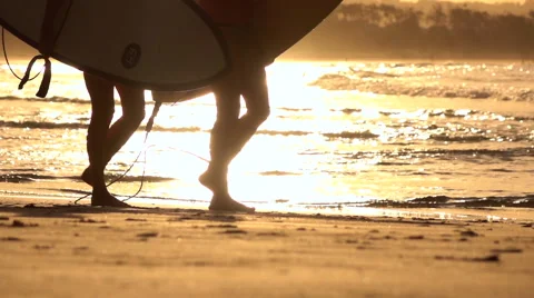 SLOW MOTION CLOSE UP: Two surfers carrying surfboards, walking along the beach Stock Footage 64739868