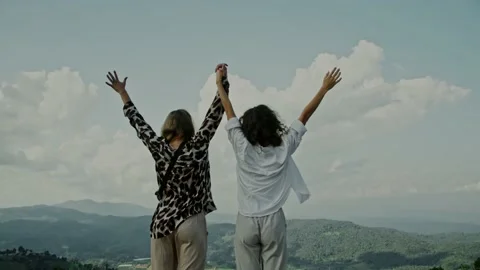 Slow motion, close-up of two young women standing on the edge of a cliff and Stock Footage 166099843