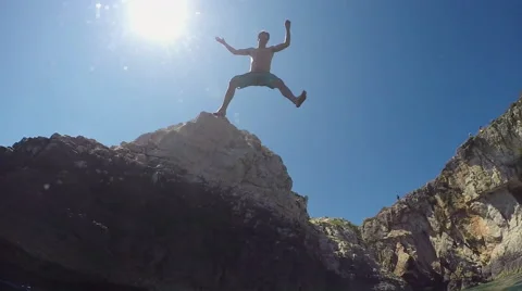SLOW MOTION CLOSE UP UNDERWATER: Man jumping off a high ocean cliff into water Stock Footage 65577407