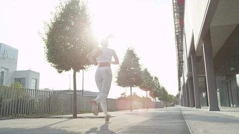 SLOW MOTION CLOSE UP: Unrecognizable athletic girl jogging on sunny day in city Stock Footage 86529318
