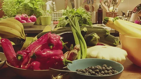Slow motion close up of various whole fruits, herbs and vegetables on a kitchen Stock Footage 273562013