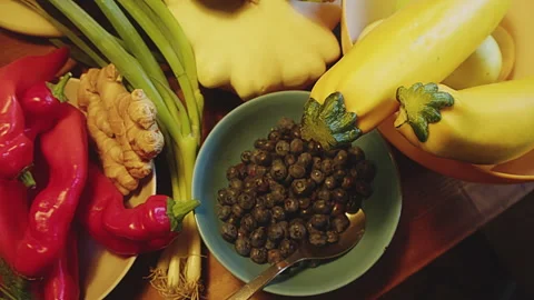 Slow motion close up of various whole fruits, herbs and vegetables on a kitchen Stock Footage 273562305