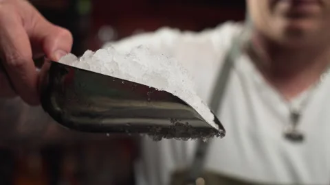 Slow motion close-up video of a bartender pouring ice into a glass. Stock Footage 229810837