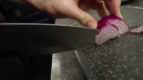 Slow motion close-up video of cutting an onion on a cutting board with a knife. Stock Footage 220768236