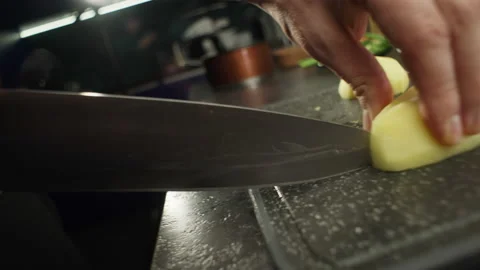 Slow motion close-up video of a knife cutting a potato on a cutting board. Stock Footage 223412193