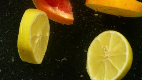 Slow motion close-up video of lemons being thrown into water on black background Stock Footage 260690951