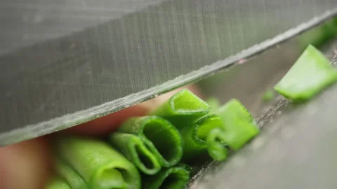 Slow motion close-up video of slicing green onions on a board with a knife. Stock Footage 220768033