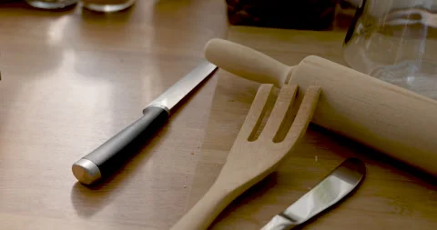 Slow motion close view moves across wooden rolling pin, spatula, butter knife, Video stock 335763575