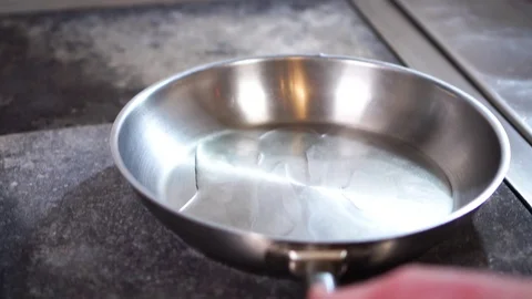 Slow motion close up view on olive oil moving slowly on clean steel frying pan Stock Footage 105457289